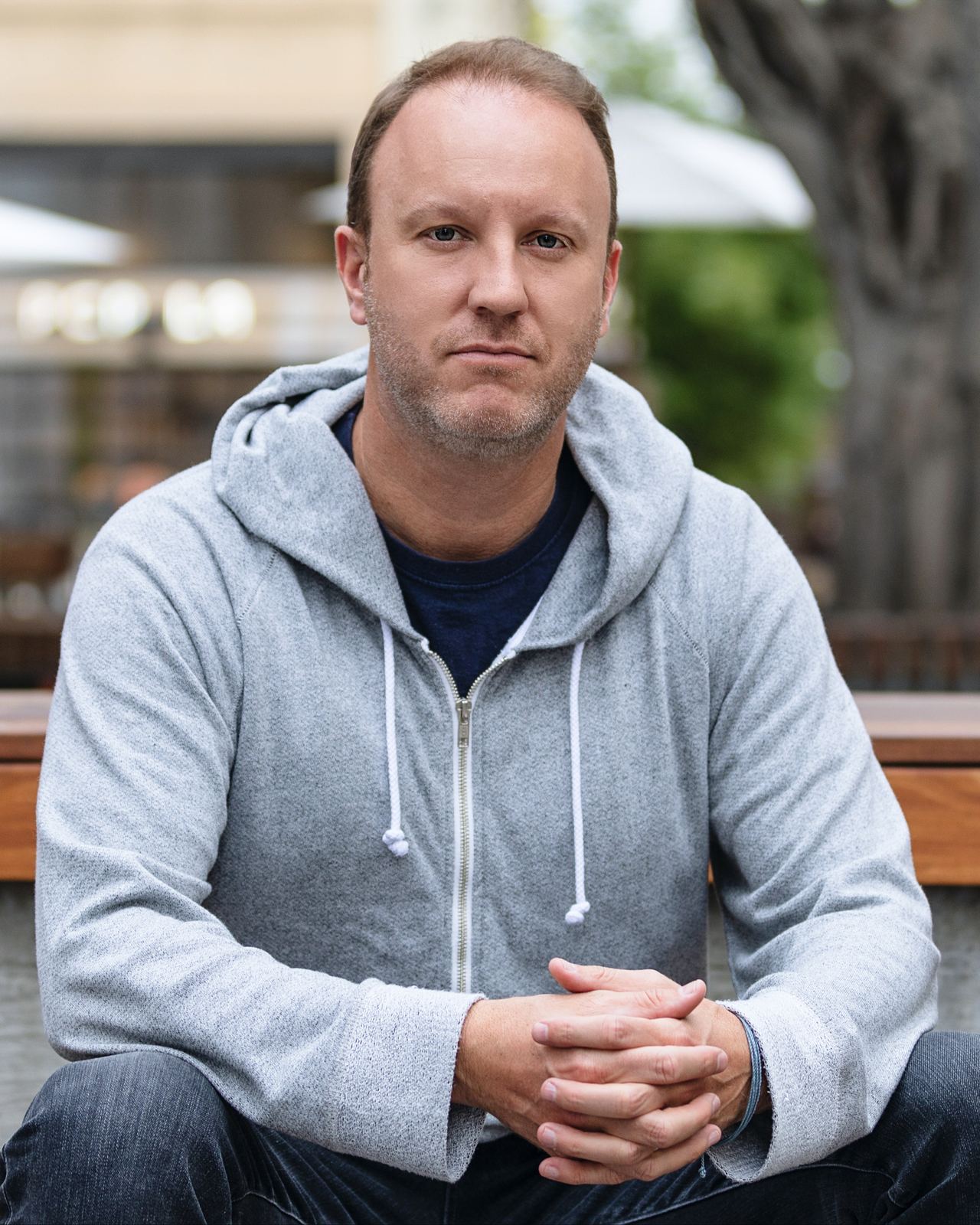 Darren Marble in a gray hoodie, seated on a bench outdoors