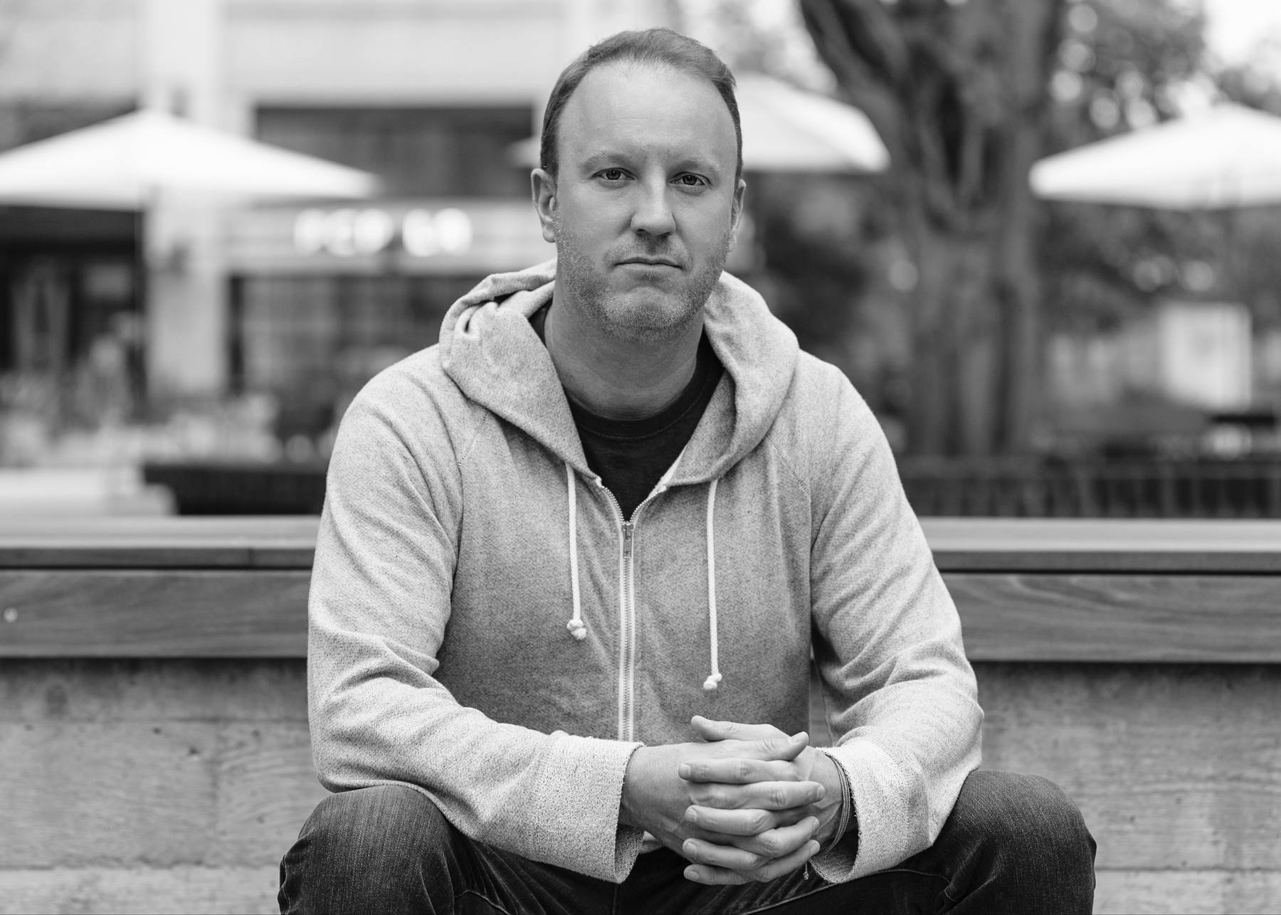 Darren Marble in a gray hoodie, seated on a bench outdoors