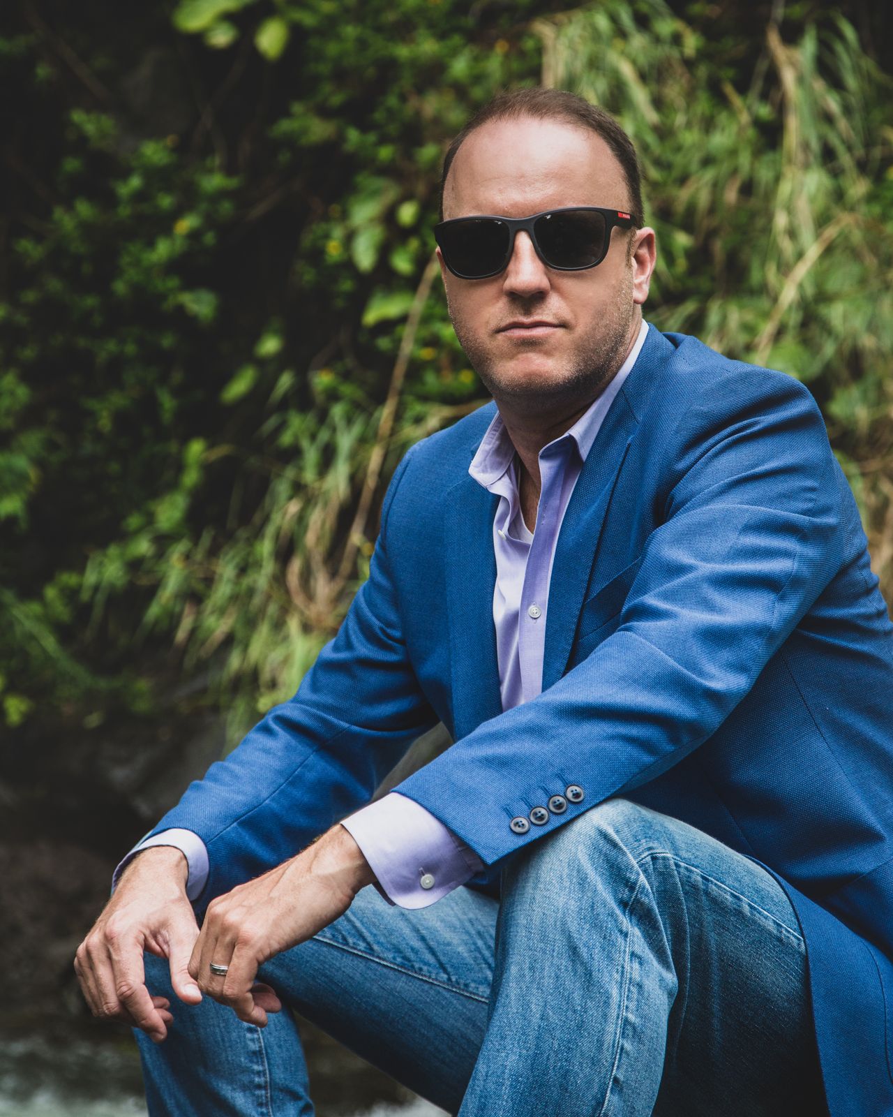 Darren Marble in a blue blazer and sunglasses, seated outdoors